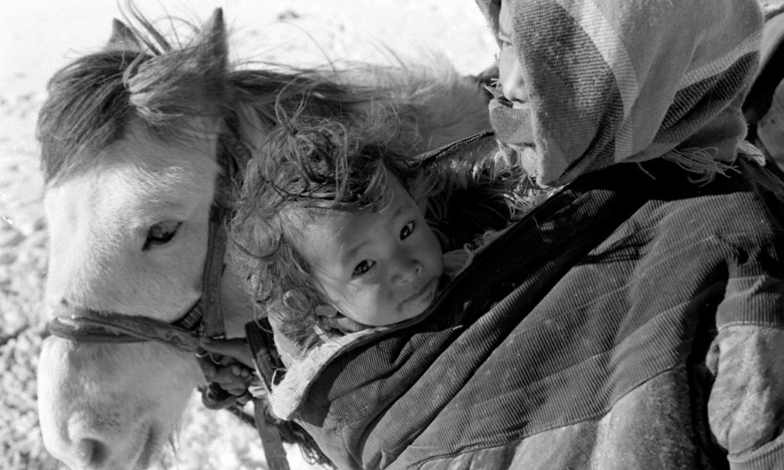 1990年3月，西藏當(dāng)雄縣納木湖鄉(xiāng)三村女牧民斯卓不畏嚴(yán)寒，懷抱幼子，準(zhǔn)備到遠(yuǎn)處放牧。新華社記者覺果攝