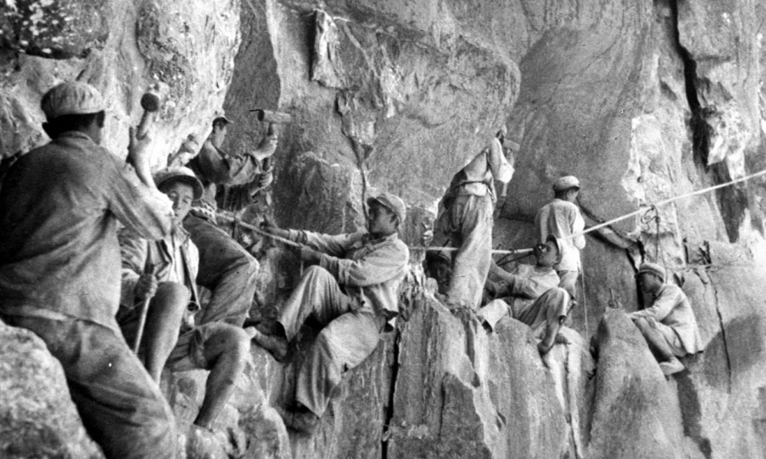 1954年，修筑康藏公路的解放軍戰(zhàn)士們在怒江兩岸的懸崖陡壁上辟山筑路。新華社稿 李萬春、張加里攝